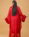 Model wearing a red organza statement dress with bow-tie neck and textured floral sleeve details, styled for formal and festive occasions.