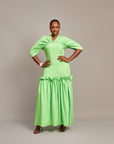 A lady wearing the Ine maxi dress featuring a draped V neckline, gathered waist detailing, and ruched hem accents.
