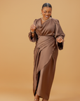 Woman wearing a coffee brown satin wrap gown with a cowl neckline and ruched waist, posing gracefully against a neutral background.