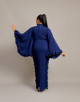 woman wearing the Tella Dress: one in ivory, one in navy. Maxi gowns with ruffle sides, long sleeves, and bow-tie neckline.
