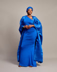 Woman wearing the Buubu Signature Set in royal blue, featuring a ruched floor-length gown, kimono overlay, and matching headwrap.

