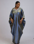 Woman wearing a shiny metallic blue-green cupped chain dress with loose sleeves and embellished neckline.
