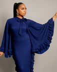 woman wearing the Tella Dress: one in ivory, one in navy. Maxi gowns with ruffle sides, long sleeves, and bow-tie neckline.
