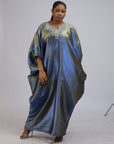 Woman wearing a shiny metallic blue-green cupped chain dress with loose sleeves and embellished neckline.
