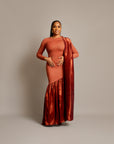 A woman wearing a sari dress with an asymmetrical neckline, gathered satin hem, and draped fabric over one shoulder.
