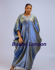 Woman wearing a shiny metallic blue-green cupped chain dress with loose sleeves and embellished neckline.
